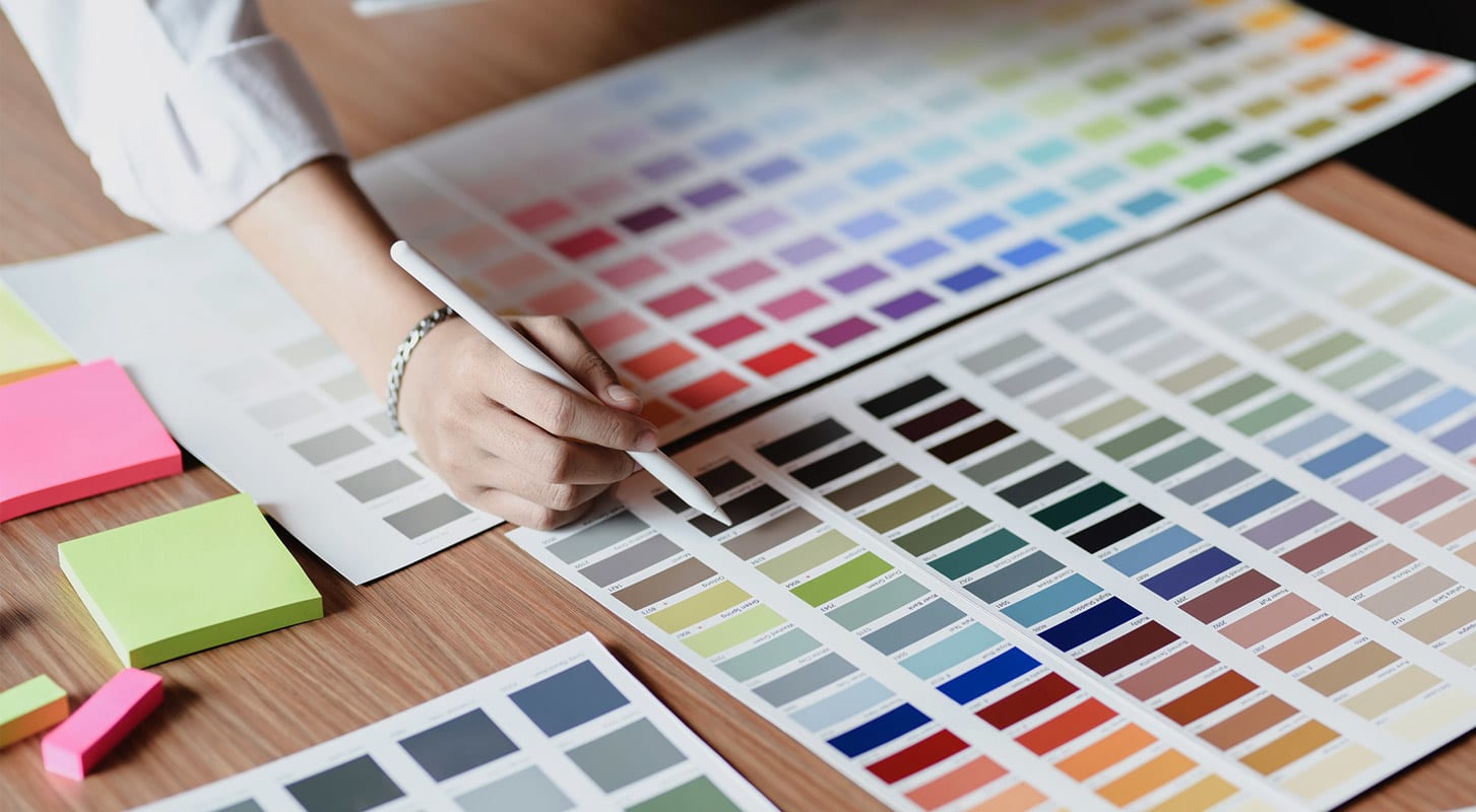 A person selecting a color from a color chart.